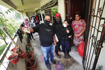 SEMANGAT BERAMAL: (Dari kiri) Sukarelawan Encik Anwar Taha dan Encik Fauzi Atan bergambar dengan Cik Mariam Jaafar semasa menghantar pek habuan ke rumah-rumah di kawasan Woodlands. - Foto BH oleh KELVIN CHNG