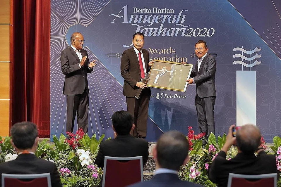 KEBANGGAAN MASYARAKAT: Encik Mohamed Faizal (tengah) menerima Anugerah Jauhari Berita Harian tahun ini daripada Encik Saat dengan diperhatikan tetamu terhormat, Encik Shanmugam (kiri). - Foto BH oleh GAVIN FOO