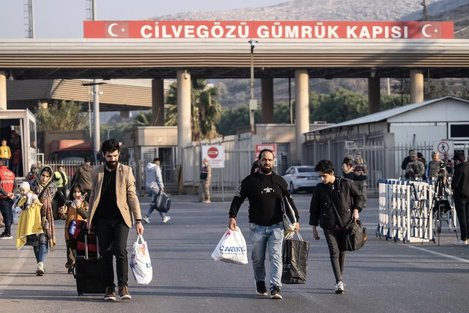 Penduduk Syria membawa barangan mereka melintasi bahagian sempadan Turkey di Pintu Sempadan Cilvegozu, yang menghubungkan Turkey dan Syria, di daerah Reyhanli, Hatay, pada 10 Disember. (Gambar sisipan) Perdana Menteri sementara Syria, Encik Mohamed al-Bashir.