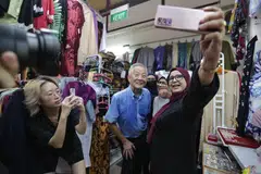 DEKATI MASYARAKAT: Encik Ng Kok Song (tengah) bergambar dengan pegerai dan pengunjung Pasar Geylang Serai semasa membuat lawatan ke sana pada Khamis.