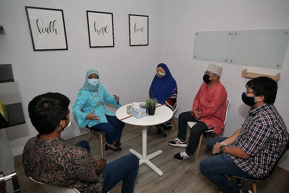 DEKATI MASYARAKAT: Puan Halimah berinteraksi (blaus hijau) dengan pekerja kes (dari kanan) Encik Bryan Chan, 30 tahun; ibu bapa angkat Encik Suhairi Rusidan, 62 tahun; Cik Normahbi Awaludin, 61 tahun; dan anak angkat mereka yang tidak boleh dinamakan, sewaktu lawatan beliau ke Trybe sebagai sebahagian pendekatan masyarakat beliau semalam. - Foto BH oleh KEVIN LIM