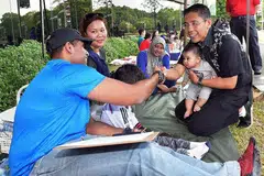 MERAIKAN NS50: Menteri Negara Kanan bagi Pertahanan, Dr Maliki Osman (mendokong bayi), berinteraksi dengan keluarga yang berkelah di Wisma Teroka Singapura semalam. - Foto MINDEF