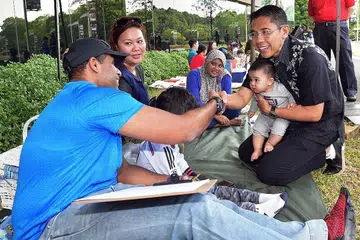 MERAIKAN NS50: Menteri Negara Kanan bagi Pertahanan, Dr Maliki Osman (mendokong bayi), berinteraksi dengan keluarga yang berkelah di Wisma Teroka Singapura semalam. - Foto MINDEF