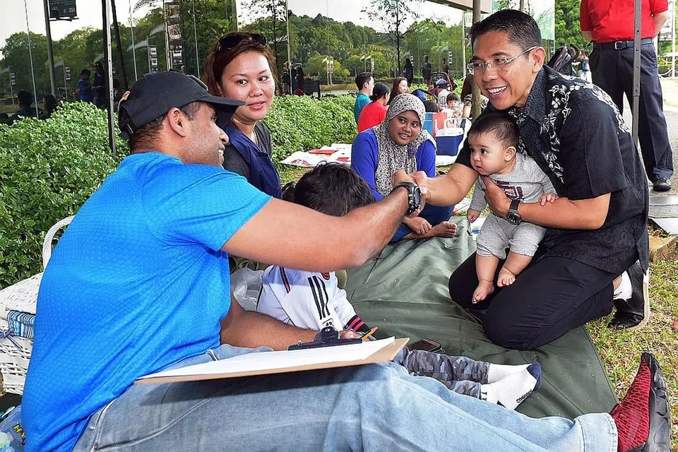 MERAIKAN NS50: Menteri Negara Kanan bagi Pertahanan, Dr Maliki Osman (mendokong bayi), berinteraksi dengan keluarga yang berkelah di Wisma Teroka Singapura semalam. - Foto MINDEF