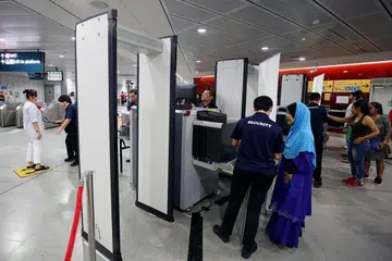 PERTINGKAT KESELAMATAN: Sebagai sebahagian daripada latihan persediaan kecemasan di Stesen MRT Holland Village (Laluan Circle) semalam, penumpang perlu melalui alat pengesanan pemeriksaan dan meletak barangan dalam sistem imbasan X-ray sebelum melepasi kawasan halangan tambang (faregate). - Foto ZAOBAO