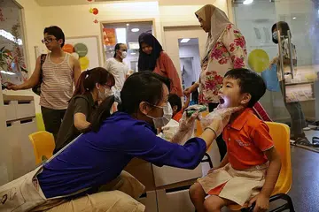 LANGKAH DIPERTINGKAT: Kakitangan My First Skool di Blok 997, Buangkok Crescent, melakukan pemeriksaan suhu badan dan visual ke atas kanak-kanak prasekolah sebagai sebahagian langkah pencegahan yang dipertingkat untuk melindungi kesihatan dan kesejahteraan kanak-kanak dan kakitangan di tengah-tengah situasi virus Wuhan ini. - Foto BH oleh KEVIN LIM