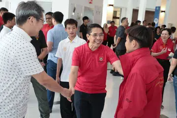 Menteri di Pejabat Perdana Menteri, yang juga Menteri Kedua (Ehwal Luar merangkap Pendidikan), Dr Mohamad Maliki Osman (tengah), berinteraksi bersama seorang atlet-pelajar dalam upacara mengucapkan selamat jalan untuk kontinjen Pasukan Sukan Sekolah Singapura sebelum ke Sukan Sekolah-Sekolah Asean di Institusi St. Joseph pada 21 Mei.