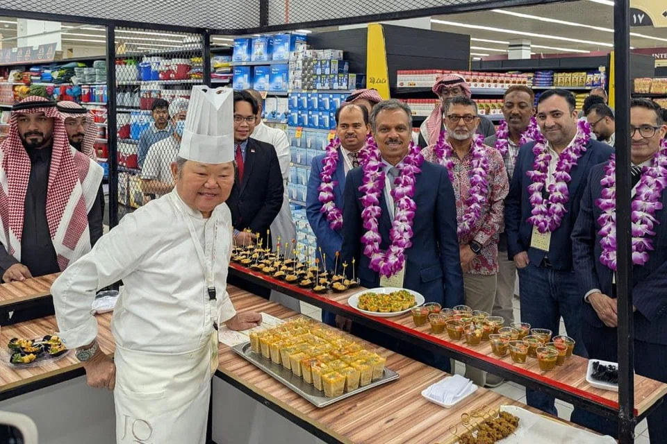 Duta Singapura, Encik Premjith Sadasivan (tengah), mencuba hidangan yang disediakan oleh cef Singapura, Cef Justin Quek (kiri). 