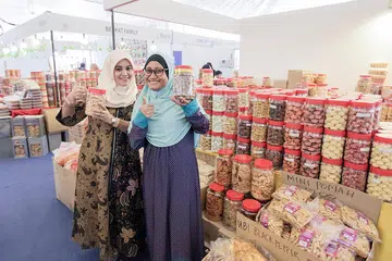 KUIH RAYA BUATAN TANGAN: Cik Zarina (kiri) bersama rakan sekerja yang mengendalikan gerai Warung Man Baba di Bazar Raya Utara. - Foto BH oleh IQBAL FAISAL
