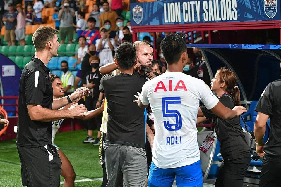 PERGADUHAN DUA PASUKAN: Pegawai dan pemain menahan penolong jurulatih Tampines, Mustafic Fahrudin (tengah), yang terlibat dalam pertembungan dengan jurulatih Lion City Sailors, Kim Do-hoon, selepas perlawanan di Stadium Jalan Besar.