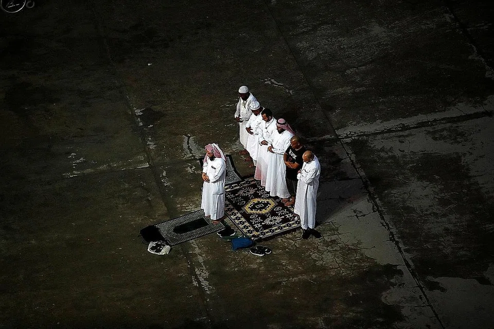 SOLAT BERSAMA: Para jemaah ini melakukan sembahyang berjemaah di sela-sela waktu di bangunan melontar jamrah - Foto REUTERS