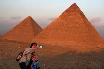 SEKTOR MENARIK: Seorang pelancong mengambil foto bersama anaknya di hadapan Piramid Besar di Giza, di luar kawasan Kahirah, Mesir. Pihak berkuasa negara itu kini ingin sekurang-kurangnya seorang dalam setiap keluarga di negara itu bekerja dalam sektor pelancongan. - Foto REUTERS