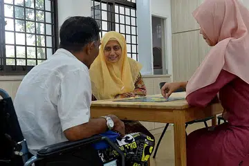 GEMBIRA DAPAT 'BERSEKOLAH': Pesakit demensia 'Encik Farid' gembira dapat ke Kelab Heal@Marsiling dan mengisi masa dengan pelbagai kegiatan merangsang minda. Bersamanya ialah Dr Radiah (tengah) dan eksekutif program Kelab Heal, Cik Rishah Zainal. - Foto TUKIMAN WARJI