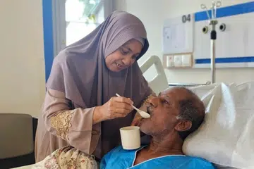 Cik Ismiati Yahya (kiri) menyuapkan suaminya, Encik Abdul Hassan Mohamed Yusof (kanan), di Hospital Masyarakat Jurong (JCH).