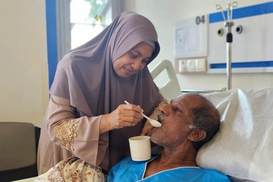 Cik Ismiati Yahya (kiri) menyuapkan suaminya, Encik Abdul Hassan Mohamed Yusof (kanan), di Hospital Masyarakat Jurong (JCH).
