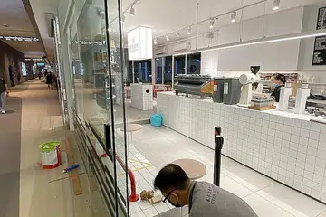 BUAT PERSIAPAN: Pekerja Dutch Colony di cawangan Our Tampines Hub sedang mengeluarkan pelekat bagi jarak selamat berikutan pelonggaran langkah pengurusan selamat yang berkuat kuasa mulai hari ini. - Foto DUTCH COLONY