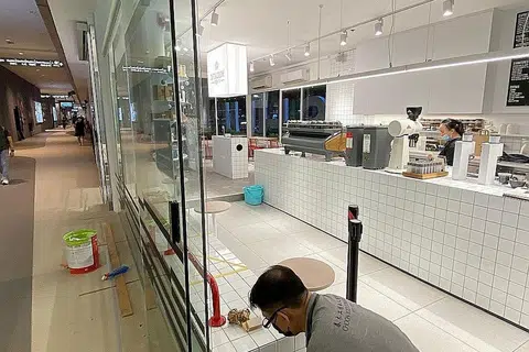 BUAT PERSIAPAN: Pekerja Dutch Colony di cawangan Our Tampines Hub sedang mengeluarkan pelekat bagi jarak selamat berikutan pelonggaran langkah pengurusan selamat yang berkuat kuasa mulai hari ini. - Foto DUTCH COLONY