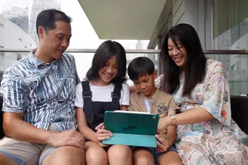 Pasangan suami isteri, Encik Ryan Quan-Chai (kiri) dan Cik Suzanne membuat pembelian secara dalam talian bersama -sama anak mereka, Charlotte (dua dari kiri) dan Jenson, sambil membimbing mereka bagaimana untuk berbelanja secara bijak.