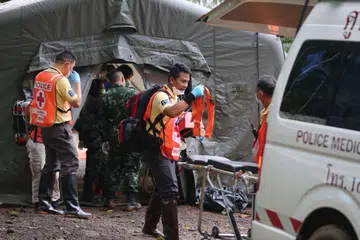 DIBERI RAWATAN: Kakitangan tentera dan polis di khemah kuarantin di kawasan gua Tham Luang kelihatan memberi bantuan selepas penyelam berjaya menyelamatkan beberapa remaja yang terperangkap semalam. - Foto AFP