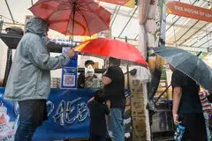 Kakitangan perniagaan sushi bakar Yodaebak menyediakan payung kepada pelanggan di Bazar Gemilang Kampong Gelam (GKG).