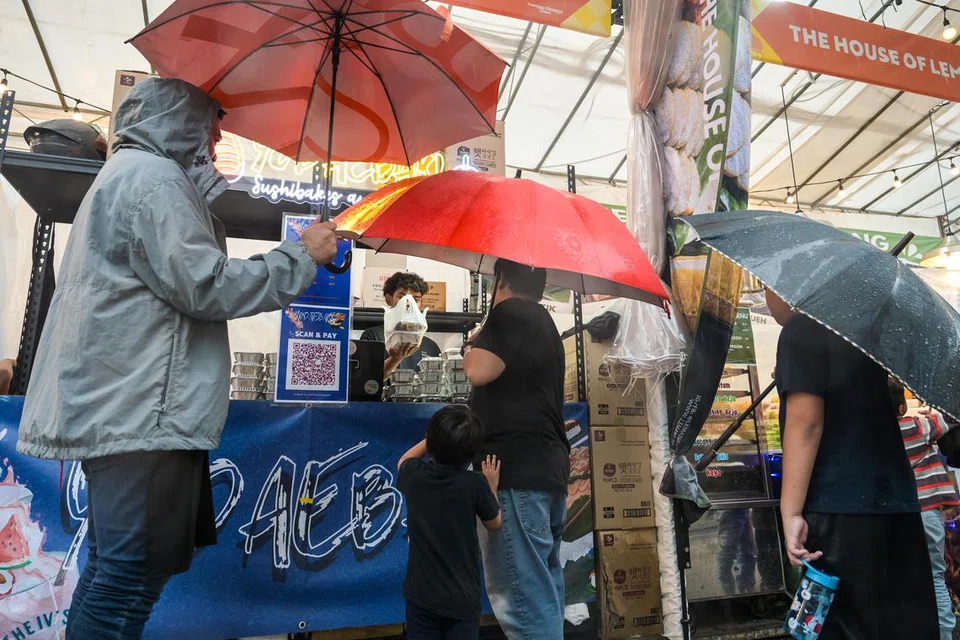 Kakitangan perniagaan sushi bakar Yodaebak menyediakan payung kepada pelanggan di Bazar Gemilang Kampong Gelam (GKG).