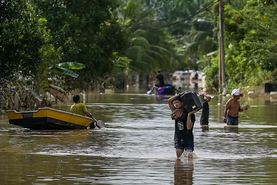 BANJIR: Para penduduk berjalan meredah banjir di Mentakab, Pahang kelmarin. Keadaan banjir di lima negeri di Malaysia menunjukkan sedikit tanda positif apabila jumlah operasi pusat pemindahan sementara (PPS) semakin berkurangan. - Foto AFP