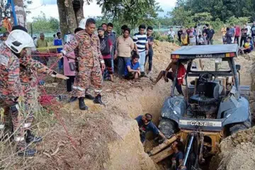 Anggota Jabatan Bomba dan Penyelamat (JBPM) membantu menggali perigi yang tertimbus tanah untuk mencari mangsa di Kampung Gelam Tok Uban, Pasir Mas, Kelantan, pada petang 15 April.
