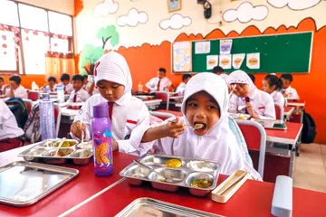 Murid-murid menikmati hidangan percuma di sebuah sekolah rendah di Depok, Jawa Barat, Indonesia, pada 6 Januari 2025. Indonesia secara rasmi memulakan Program Makanan Berkhasiat Percuma (MBG) dengan 190 dapur beroperasi di 26 wilayah bagi memenuhi keperluan pemakanan nasional.