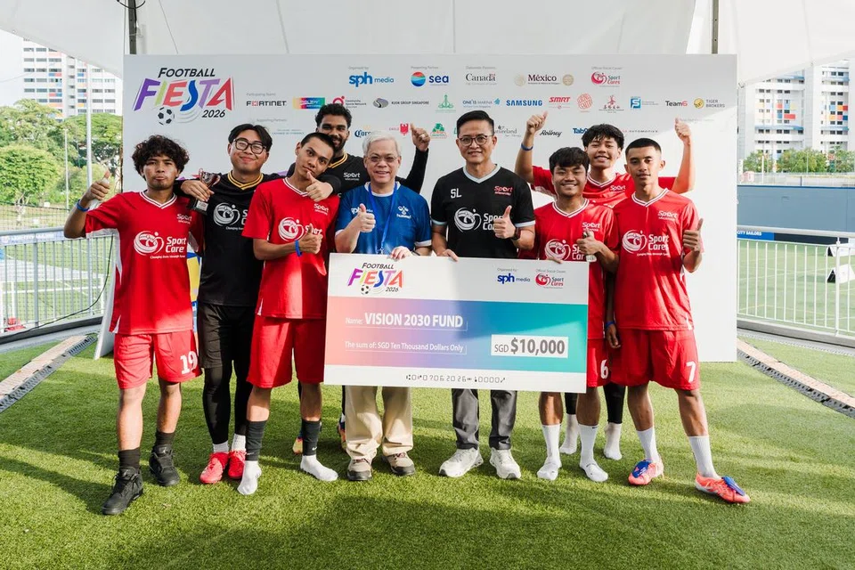 Ketua Pegawai Eksekutif (CEO) SPH Media, Encik Chan Yeng Kit (lima dari kiri) menyampaikan cek bernilai $10,000 kepada Pengarah SportCares, Encik Shawn Lim (empat dari kanan). Turut bergambar bersama mereka adalah pasukan bola sepak dari SportCares.