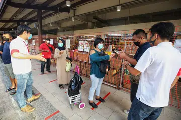 IMBAS KAD PENGENALAN: Pengunjung ke Pasar Geylang Serai perlu mengimbas kad pengenalan mereka sebagai sebahagian langkah 'SafeEntry' bagi tujuan menjejak kontak. - Foto fail