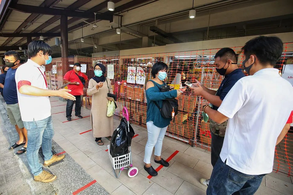 IMBAS KAD PENGENALAN: Pengunjung ke Pasar Geylang Serai perlu mengimbas kad pengenalan mereka sebagai sebahagian langkah 'SafeEntry' bagi tujuan menjejak kontak. - Foto fail