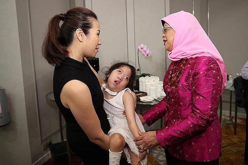 IBU ISTEMEWA: Presiden Halimah (kanan) bersama Cik Jasmine Lee dan anaknya, Sarah, yang dilahirkan dengan penyakit luar biasa yang menyebabkan dia terlantar di katil. Dedikasi dan pengorbanan Cik Jasmine antara dua ibu contoh yang turut disebut Presiden Halimah dalam pos di Facebooknya sempena Hari Ibu semalam. - Foto FACEBOOK HALIMAH YACOB