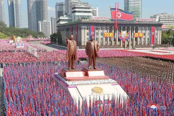 PERARAKAN: Para peserta mengibarkan bendera semasa satu perarakan tentera sempena ulang tahun Korea Utara yang ke 70 di Pyongyang. - Foto REUTERS
