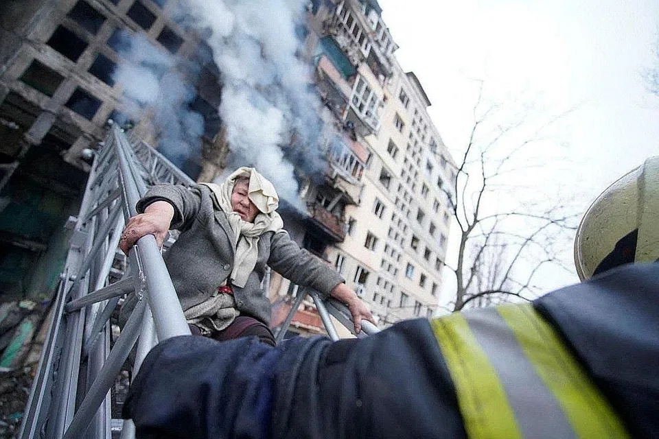 SELAMATKAN MANGSA SERANGAN: Penyelamat sedang membantu seorang wanita tua keluar daripada tempat kediamannya selepas bangunan yang dihuninya di Kyiv dibedil tentera Russia. - Foto REUTERS