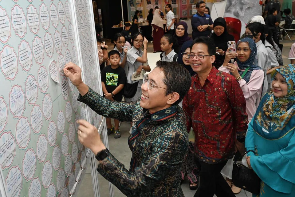 PAPARAN PANTUN ASLI MELAYU TERBESAR: Menteri di Pejabat Perdana Menteri yang juga Menteri Kedua (Ehwal Luar merangkap Pendidikan), Dr Mohamad Maliki Osman, yang juga pengerusi Pembelajaran dan Penggalakan Penggunaan Bahasa Melayu, melekatkan pantun ditulisnya di dinding di Fiesta Bahasa 2023 pada Sabtu, acara yang mencatatkan rekod bagi ‘Paparan Pantun Melayu Asli Terbesar’ di dalam Buku Rekod Singapura.