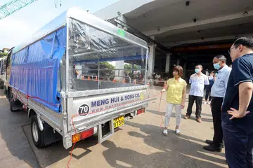 LEBIH SELESA: Dr Khor (kiri) melihat contoh lori yang digunakan untuk membawa pekerja yang dipasang dengan penutup hujan, bersama (dari kanan) Pengarah Kumpulan Perkhidmatan Kenderaan LTA, Encik Alvin Chia; Pengarah Urusan Quek & Quek Civil Engineering Pte Ltd, Mr Quek Hong Peng; Pengurus EHS Quek & Quek Civil Engineering, Encik Mr Francis Ong Yew Lee. - Foto ZAOBAO