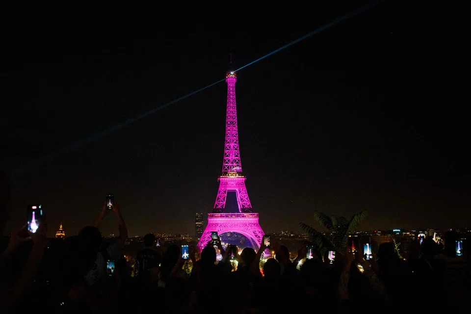 DISINARI CAHAYA: Orang ramai yang berkumpul di medan Trocadero di Paris, Perancis, mengambil gambar Menara Eiffel yang diterangi cahaya merah jambu semasa pelancaran Bulan Kesedaran Barah Buah Dada. 