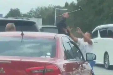 Tangkap layar video tular menunjukkan lelaki dipercayai warga asing (tengah) yang memandu Mitsubishi Lancer menggunakan tongkat kayu ketika bergaduh. 