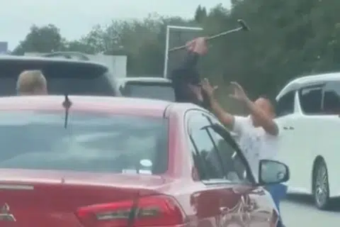 Tangkap layar video tular menunjukkan lelaki dipercayai warga asing (tengah) yang memandu Mitsubishi Lancer menggunakan tongkat kayu ketika bergaduh. 