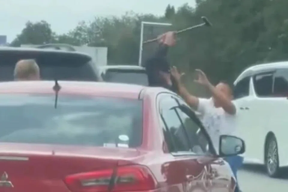 Tangkap layar video tular menunjukkan lelaki dipercayai warga asing (tengah) yang memandu Mitsubishi Lancer menggunakan tongkat kayu ketika bergaduh. 