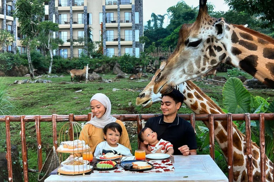 Cik Syakirah Iqbal bersama suaminya, Encik Irfan Ahmed, dan anak-anak (dari kiri) Zaheer Ahmed dan Bilal Ahmed, bersarapan bersama zirafah di Baobab Safari Resort di Surabaya.