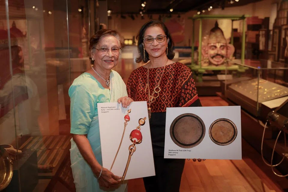 Cik Salma Moiz (kiri) bersama anaknya Cik Azra Moiz menunjukkan gambar artifak-artifak dan alat mehendi di acara rumah terbuka Pusat Warisan India Singapura.