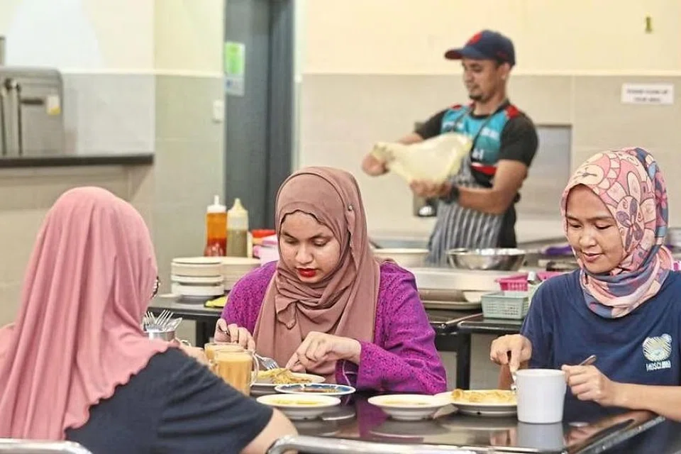 Pelanggan asyik menikmati hidangan mereka sedang  pembuat roti canai sibuk menyiapkan pesanan di sebuah restoran di Malaysia.  