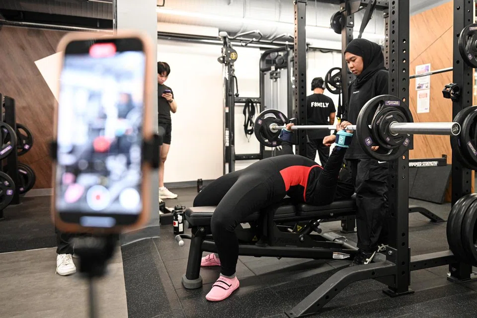 Nur Nazihah Hasan (kanan) membantu rakannya, Hannah Salim, yang sedang melakukan ‘bench press’, atau juak baring. 
