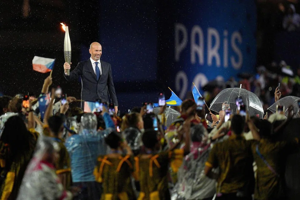 Bekas pemain bola sepak pasukan nasional Perancis, Zinedine Zidane, memegang obor Olimpik semasa upacara pembukaan Sukan Olimpik 2024.