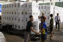Para pekerja suruhanjaya pilihan raya bekerja keras mengangkat  barang keperluan mengundi di pusat pembahagian di Denpasar, Bali, Indonesia, pada 12 Februari.