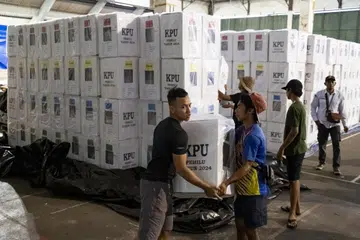 Para pekerja suruhanjaya pilihan raya bekerja keras mengangkat  barang keperluan mengundi di pusat pembahagian di Denpasar, Bali, Indonesia, pada 12 Februari.