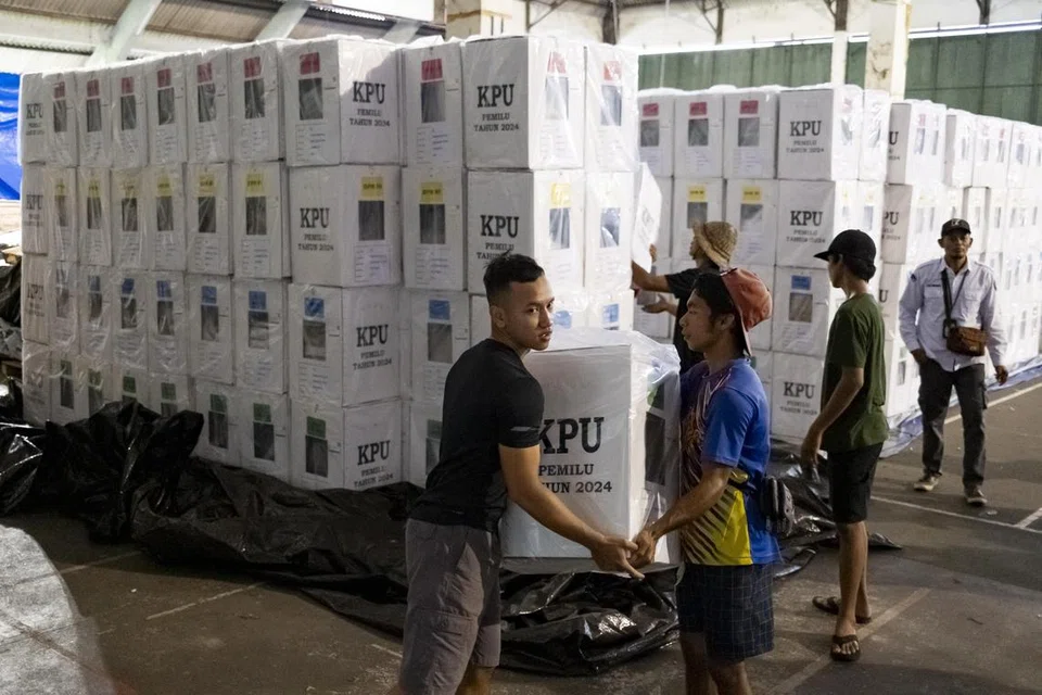 Para pekerja suruhanjaya pilihan raya bekerja keras mengangkat  barang keperluan mengundi di pusat pembahagian di Denpasar, Bali, Indonesia, pada 12 Februari.