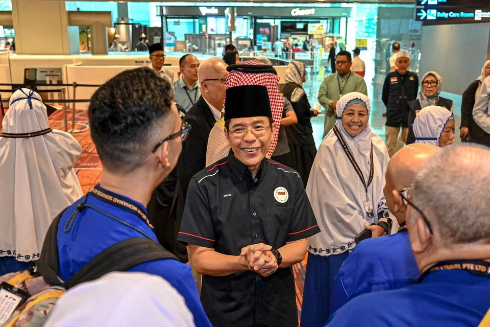 Menteri di Pejabat Perdana Menteri, Dr Mohamad Maliki Osman (baju hitam), beramah mesra dengan para jemaah haji dan keluarga mereka di Lapangan Terbang Changi pada 3 Jun.