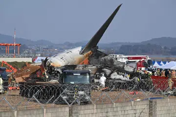 Pasukan bomba dan penyelamat berhampiran serpihan pesawat Jeju Air Boeing 737-800 yang terhempas dan terbakar di Lapangan Terbang Antarabangsa Muan, di Wilayah Jeolla Selatan, kira-kira 288 kilometer ke barat daya Seoul, pada 29 Disember 2024. 